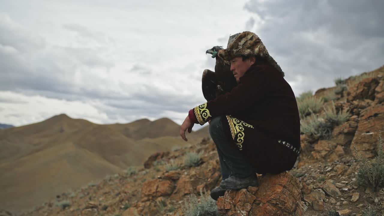 Golden eagle hunter on rocky hillside in Altai Mountains, waiting to release bird
