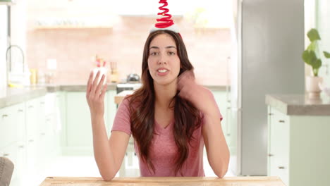 christmas time, woman wearing festive headband sitting in kitchen, enjoying holiday spirit