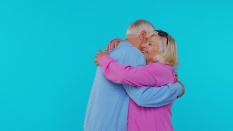 Romantic-senior-couple-man-woman-grandparents-hugging,-embracing,-looking-at-camera-and-smiling