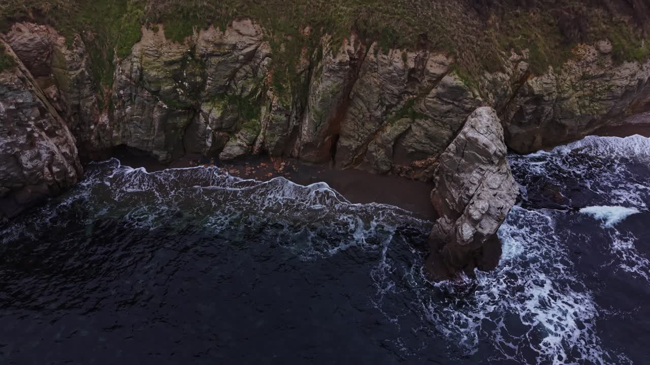 Costa frastagliata con onde che si infrangono sulle scogliere rocciose