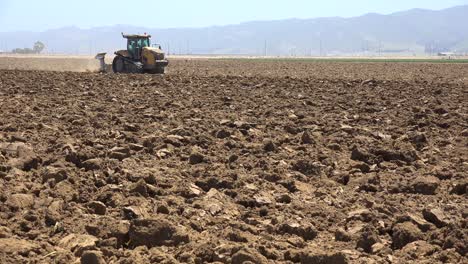 farm tractor moves across dry dusty landscape in california suggesting drought and climate change 4