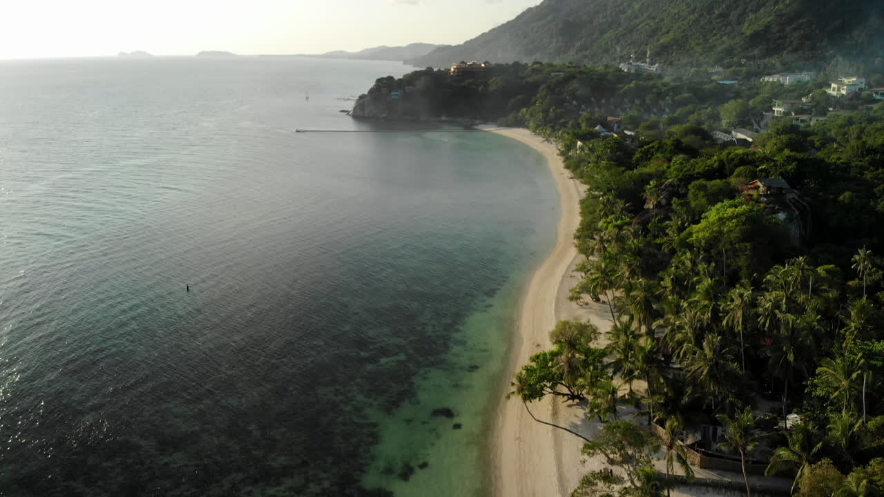 grúa disparada por drones de una hermosa playa en tailandia, con una niebla sobre los árboles