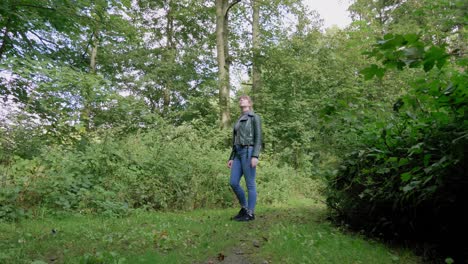 Young-woman-stands-alone-in-green-wood-looking-around,-dolly