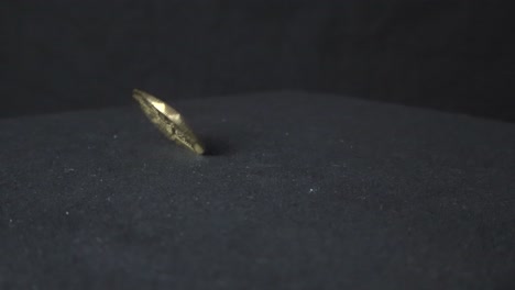bitcoin es una moneda de criptomoneda de color amarillo dorado que gira en cámara lenta sobre un fondo oscuro y una mesa que crea reflejos y sombras en la superficie oscura debajo.