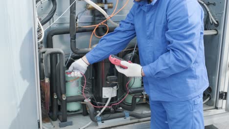 the technician checking power lines of the heat exchanger with current clamps