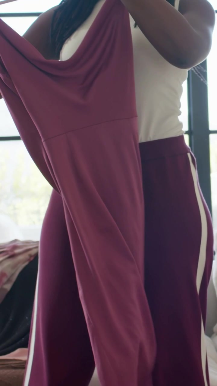 Vertical video: Entering woman in top opening maroon dress on hanger at home, checking, copy space
