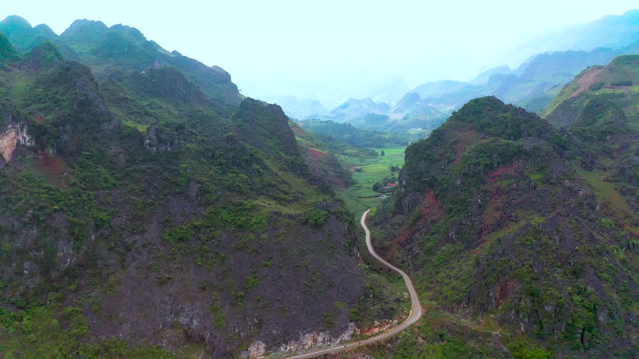 오토바이의 바쁜 도로는 베트남 북부의 안개 낀 뒷산 사이에 두 개의 산을 가로지릅니다.