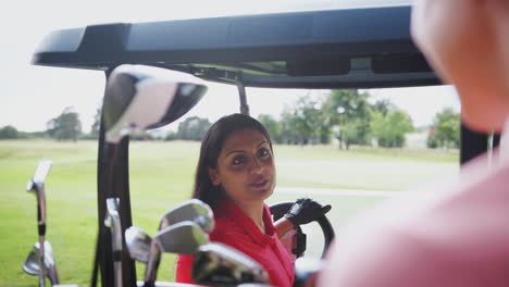 two mature female golfers sitting in buggy course on course and talking