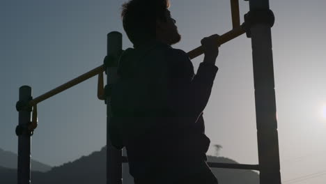 man doing pull-ups at a outdoor gym