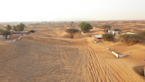 Aerial-view-of-an-empty-abandoned-village-and-homes-covered-in-desert-sand-near-Dubai