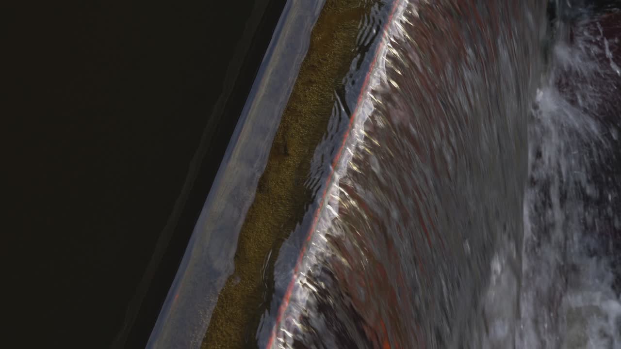 물은 댐 능선의 상부를 통해 아래로 계단식으로 흐릅니다.