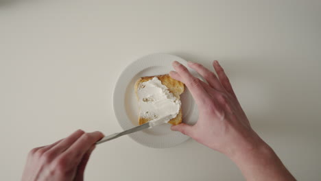 Männliche-Hände-Verteilen-Frischkäse-Auf-Toast-In-Der-Küche-Mit-Buttermesser