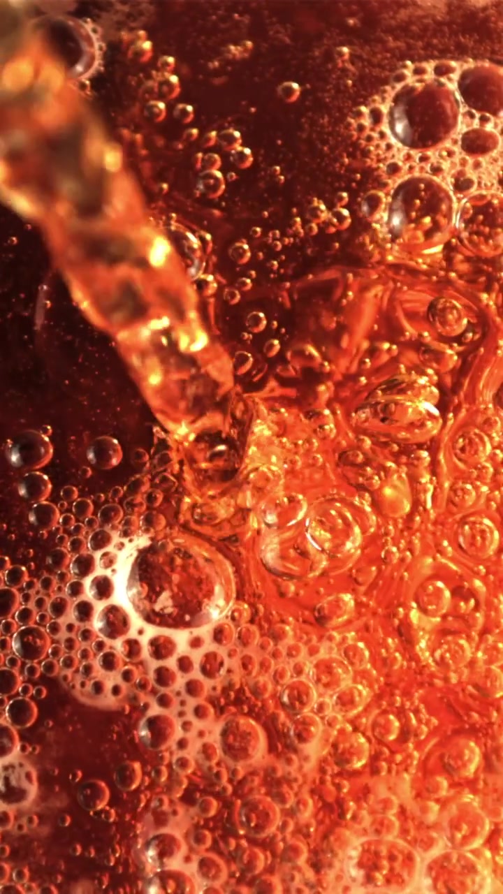 Primo piano di liquido ambrato che si versa e crea bolle