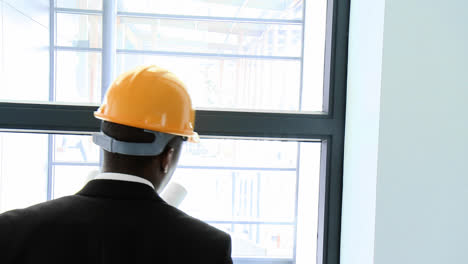 afroamerican architect studying a building and talking on phone