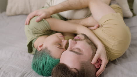 happy couple embracing and sleeping face to face on the bed at home