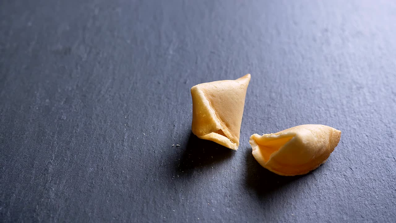 Carrellata ravvicinata di un biscotto rotto con messaggio su uno sfondo di tavolo grigio