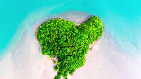 drone shot of heart shaped island in railay thailand with boats passing by