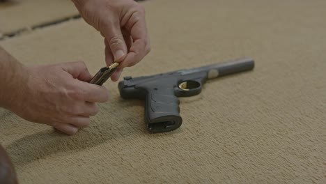 man loading pistol magazine with small caliber bullets