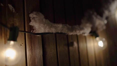 outdoor patio lights hanging on a fence, covered in snow, slow motion pan