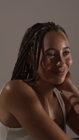 studio beauty shot of smiling young woman with long braided hair against neutral background 2