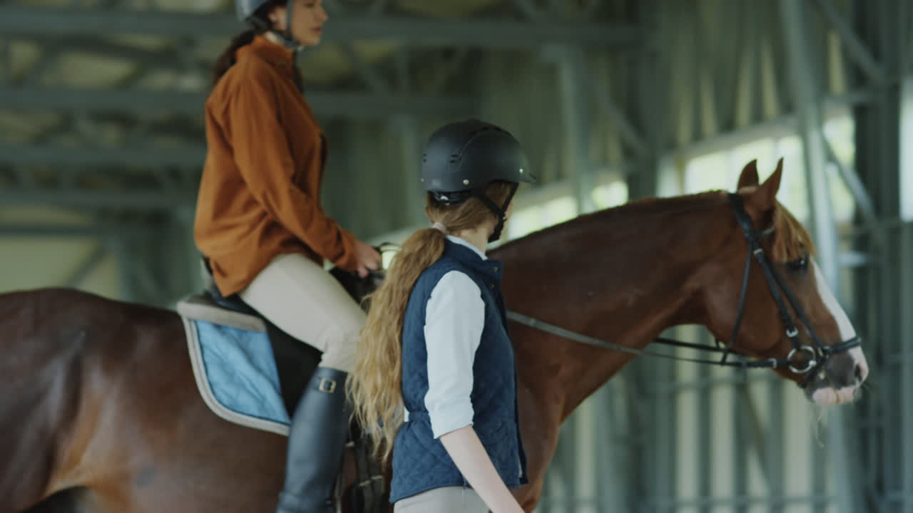 Two women and a horse in an indoor riding arena