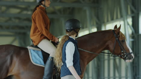 two women and a horse in an indoor riding arena