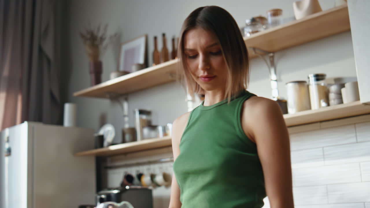 A woman in a kitchen pouring water into a glass