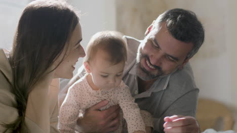 padres amorosos y su linda niña acostada en la cama y viendo dibujos animados en una tableta digital el domingo por la mañana 2