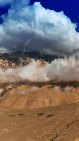 Soft white cloudscape coating the tops of mountains. View on Death Valley from aerial perspective. Vertical video