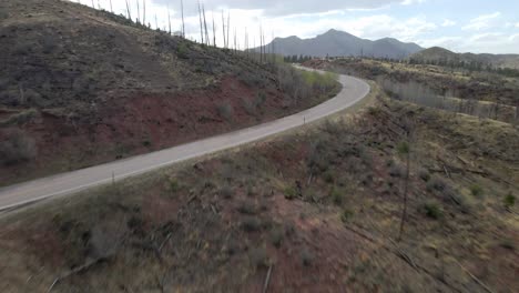 Aerial-view-moving-forward-towards-and-over-a-remote-mountain-road-in-the-Pike-National-Forest,-Rocky-Mountains,-Colorado