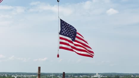 hung from a construction crane, the flag of the united states waves in the wind