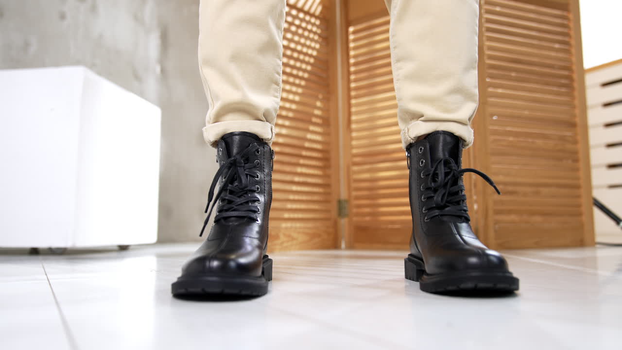 Model wearing light pants demonstrating comfortable warm boots with laces in front of camera. Studio footwear presentation close up.