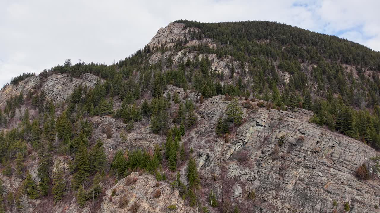 Una ripresa aerea con drone di un'aspra cresta montuosa rocciosa con pini sempreverdi nella natura selvaggia vicino a Whitefish, Montana, e il fiume Flathead