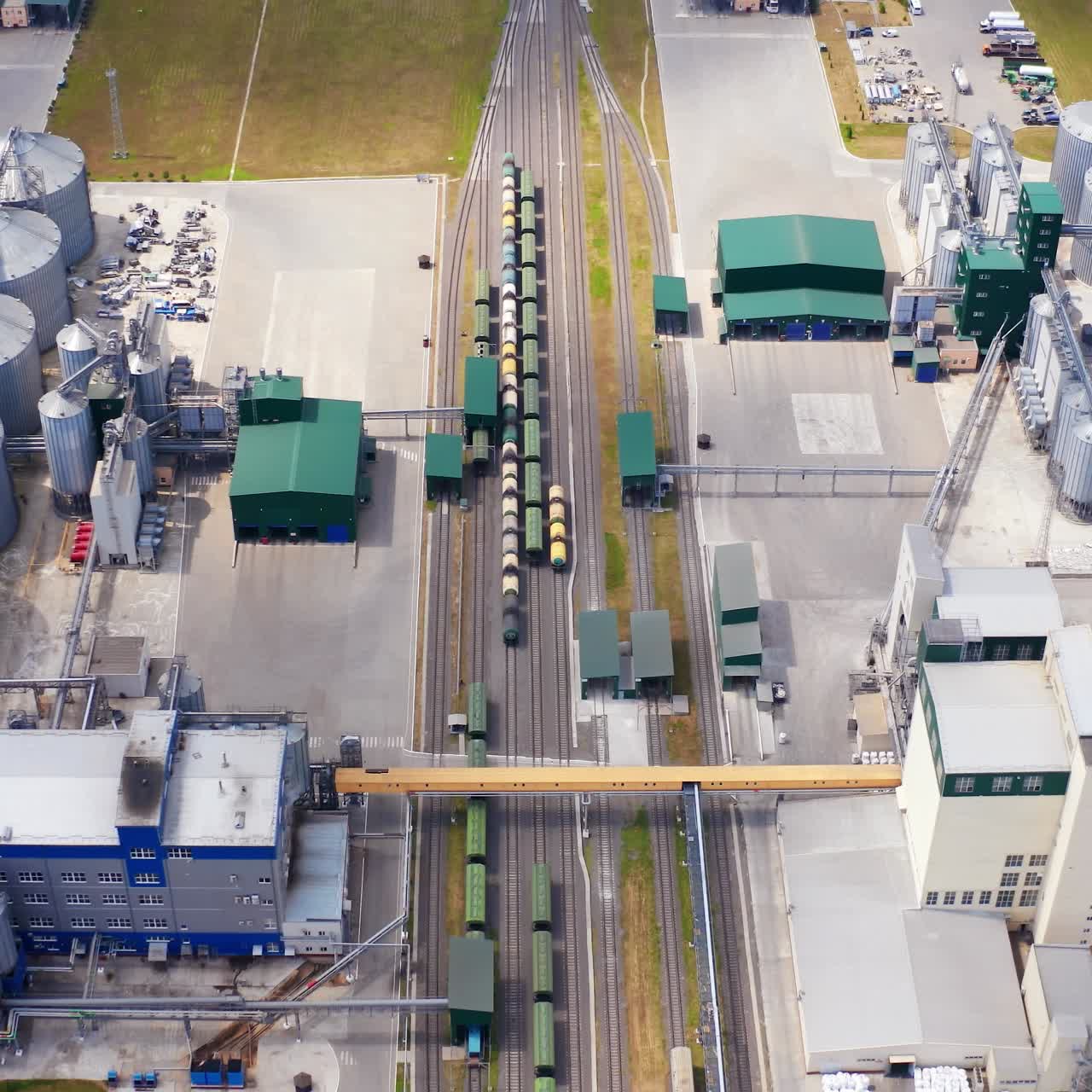 Modern industry on field. Grain processing factory with cargo trains and large metal grain elevators. View from above