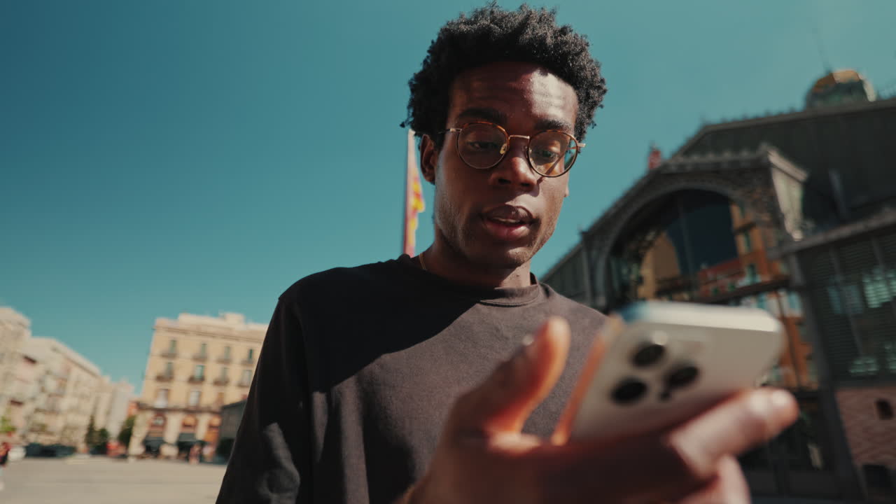 Ung afrikansk-amerikansk mann som bruker smarttelefon og snakker utendørs