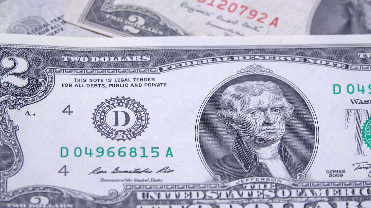 초록색 봉이 있는 2달러 지폐가 은 봉이 있는 오래된 지폐 위에 있습니다.