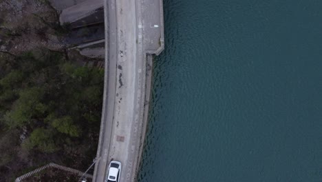 top view shot of a hydroelectric dam and the nearby lake . white cars driving over the dam | 4k