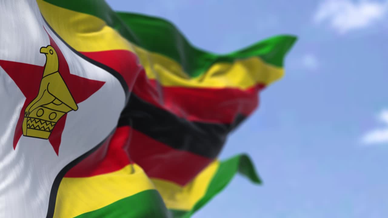 Dettaglio della bandiera nazionale dello Zimbabwe che sventola al vento in una giornata limpida.