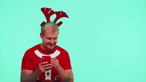 Man-in-t-shirt-Santa-Christmas-with-mobile-phone-showing-pointing-empty-place,-advertising-area