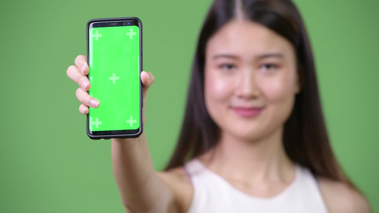 젊은 아름다운 아시아 사업가 여성이 전화를 보여주고 있습니다.