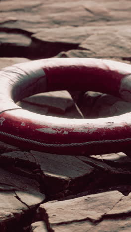 a weathered red life preserver on rocks