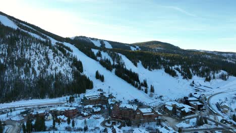 high aerial drone flying to the ski resort of winter park colorado on a winter day with people skiing.