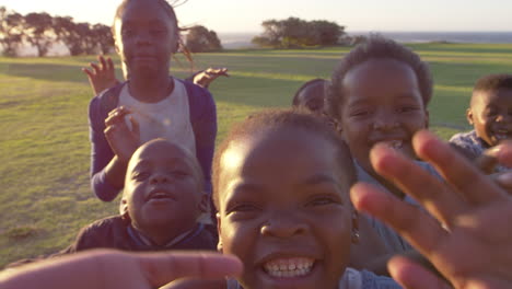 elementary school kids waving to camera outdoors, close up