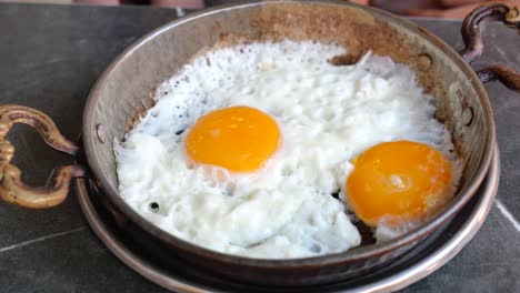 dos huevos fritos en una sartén