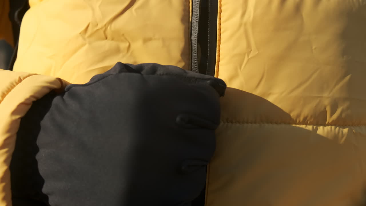 Food delivery man on a scooter in a park, zipping up his jacket and looking into camera. Black medical mask. Winter