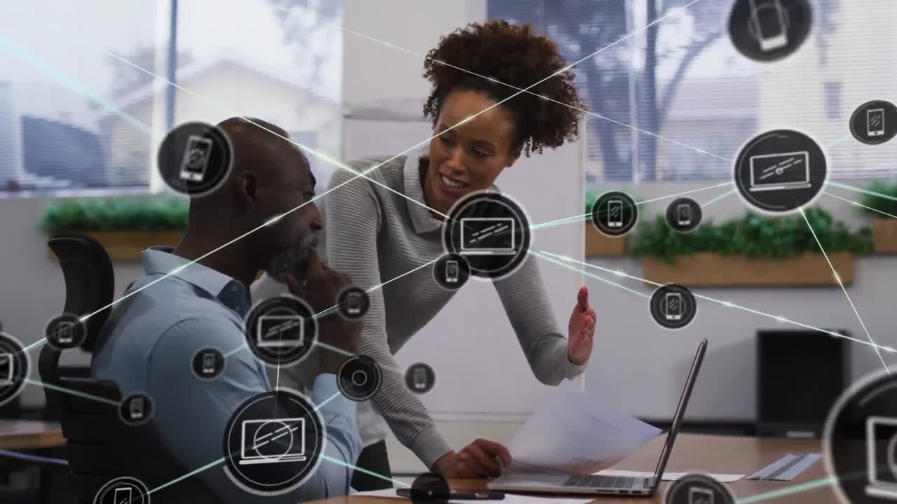 Animation of connected icons over diverse coworkers discussing reports on laptop in office