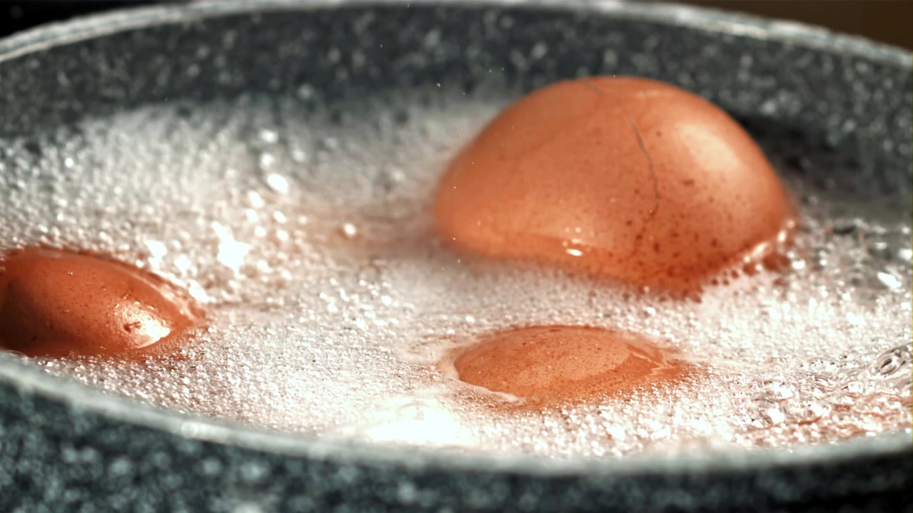 Brown Eggs Boiling in a Pot with Bubbles and a Cracked Shell