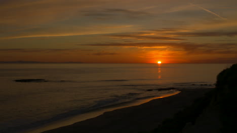 Time-lapse-of-a-beautiful,-bright-orange-sunset-over-the-Pacific-Ocean-in-California