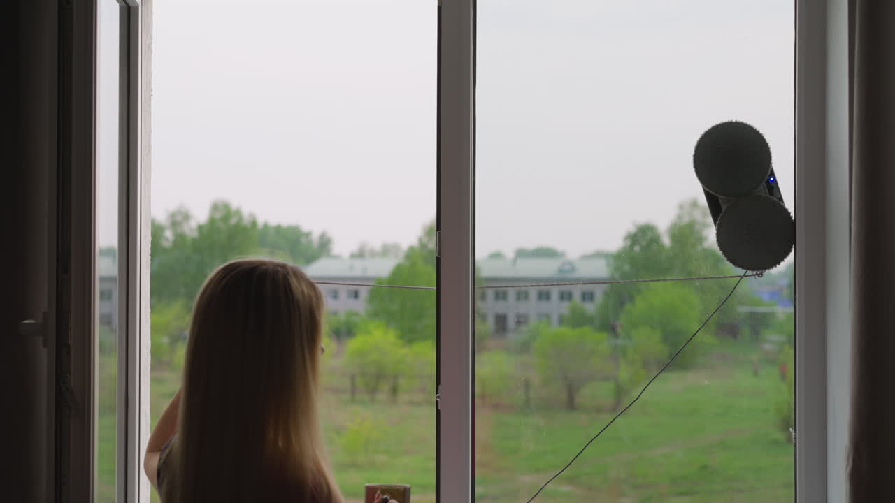 하녀가 로 ⁇  창을 청소하는 자동 로 ⁇ 을 제어하는  ⁇ 줄을 당기고