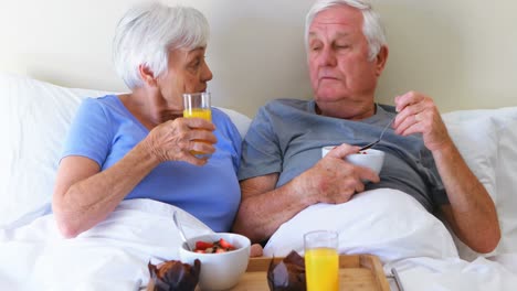 smiling couple having breakfast on bed